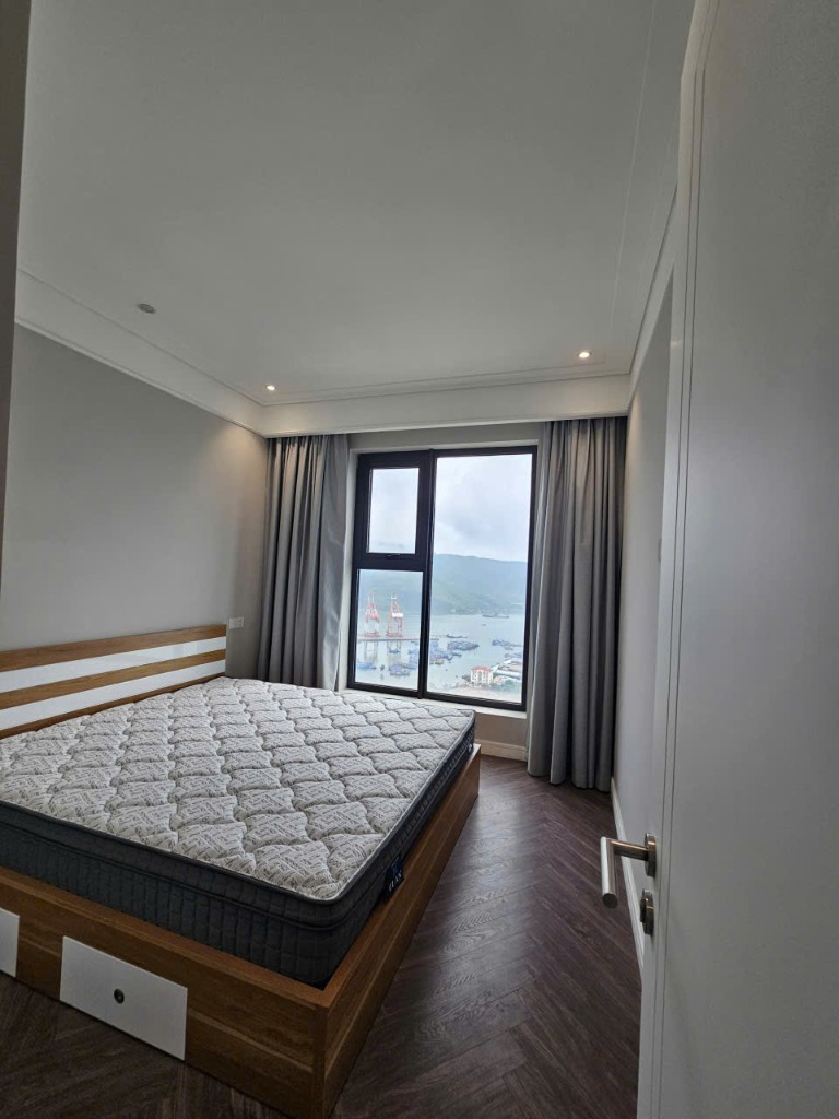 Phòng ngủ thực tế có cửa sổ nhìn thẳng ra biển và núi Hải Minh tại căn hộ Altara Residences Quy Nhơn